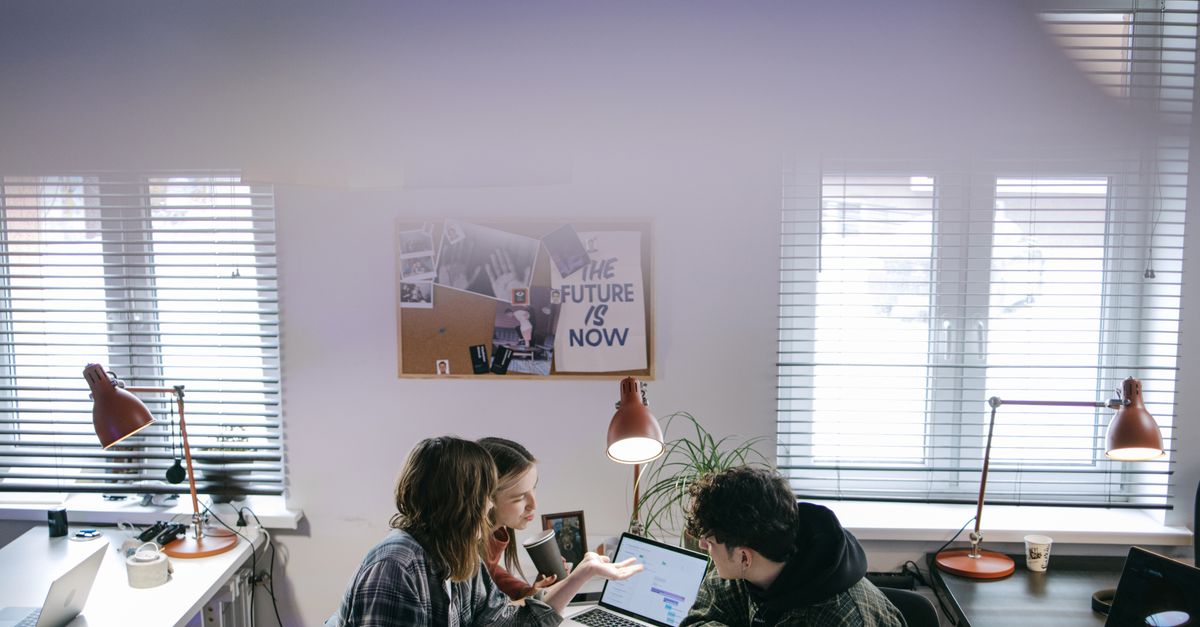 A group of people discussing ideas around laptops in a bright, modern office space.
